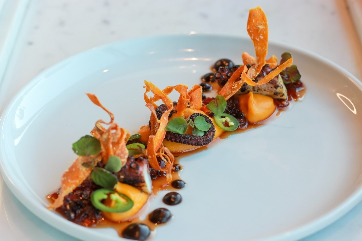 white plate with octopus and colored sauce