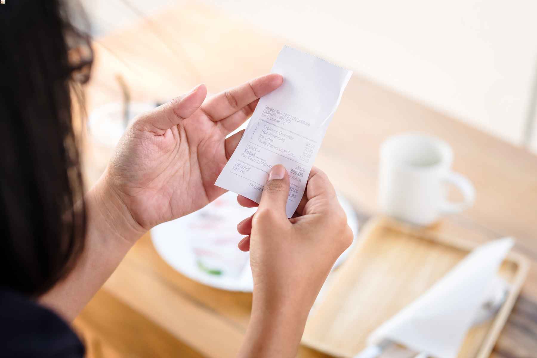 Woman examining her bill listing service fee at a restaurant.