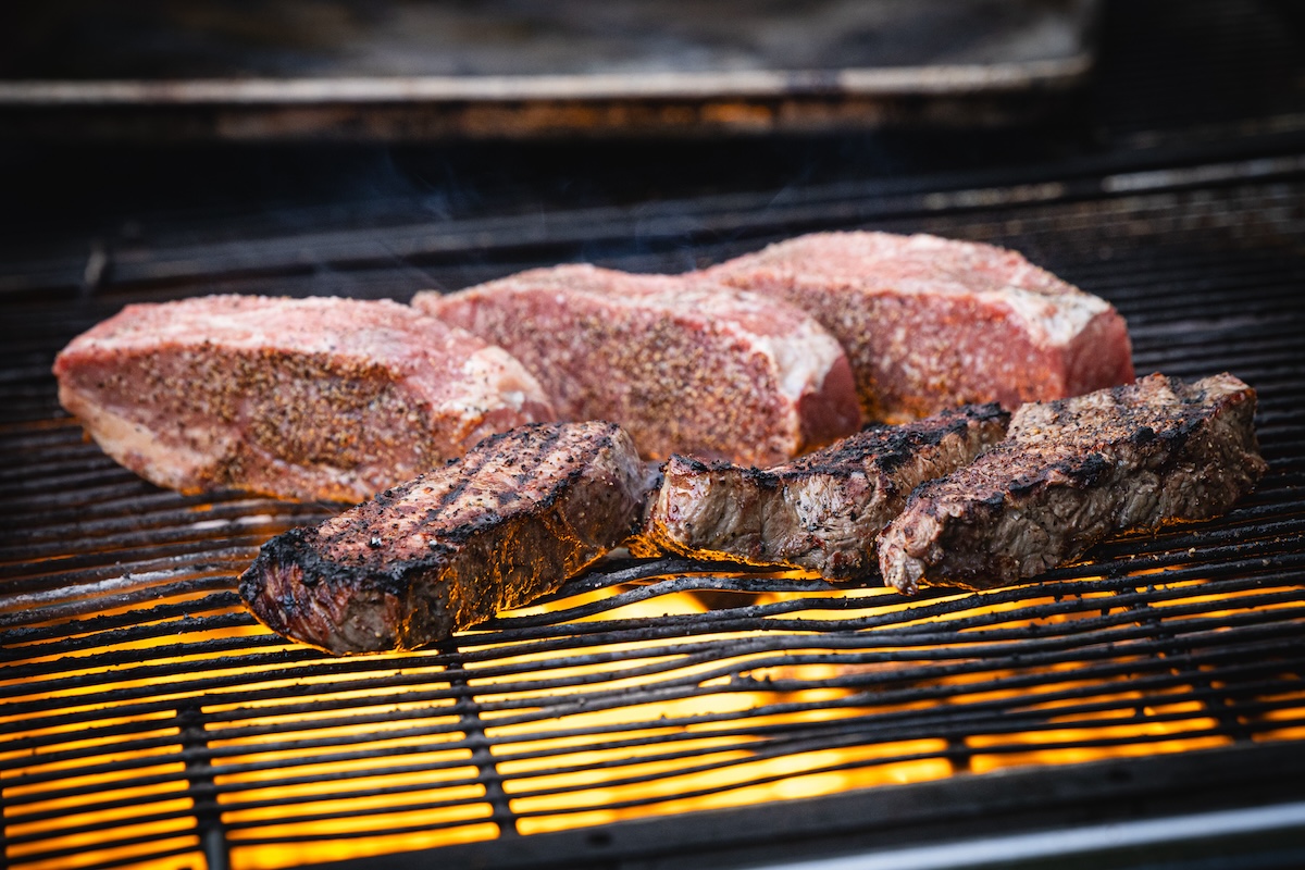 Rare2024-187 Beautiful strip steaks sizzling on the grill. | Photo by DiningOut Events