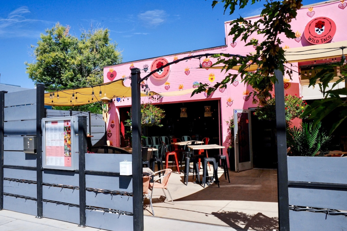 Wild_Taco_Berkeley Wild Taco Berkeley’s bright pink exterior features heart murals and outdoor seating with string lights, colorful chairs, and a shaded patio area.