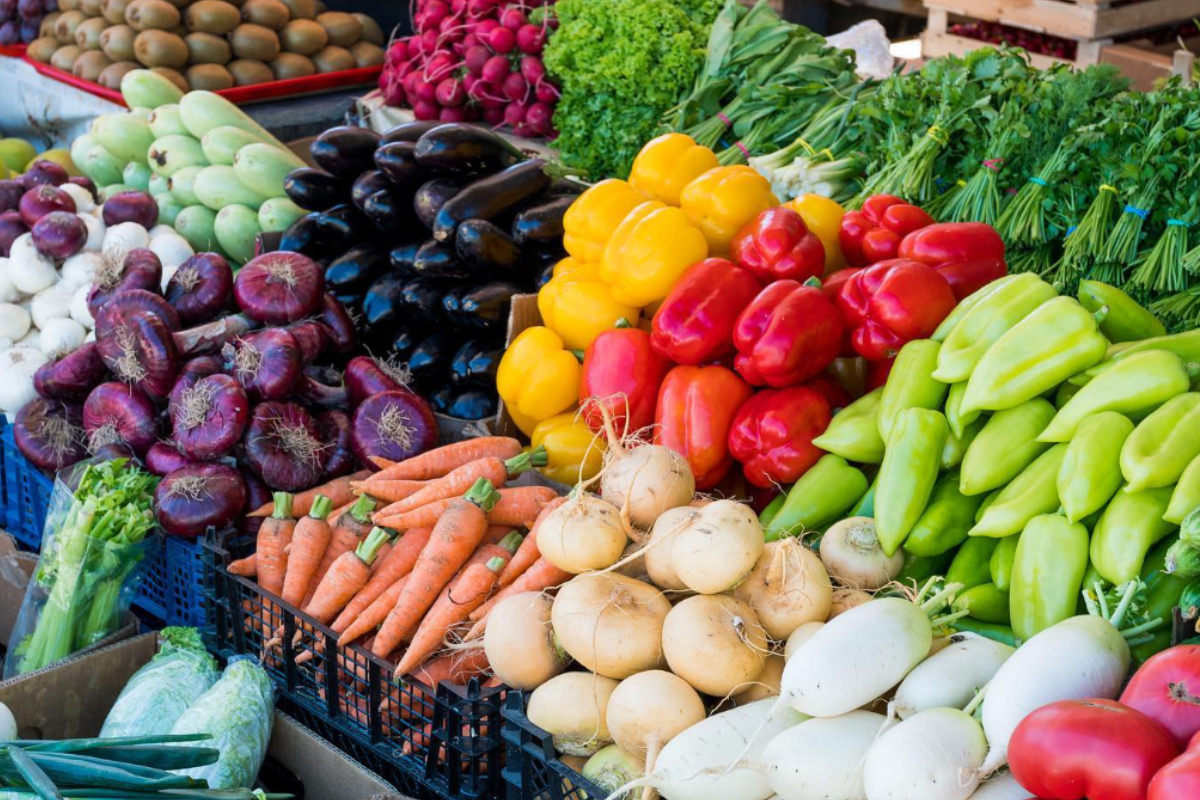 central park farmers market Colorful vegetables including bell peppers, carrots, onions, eggplants, and radishes neatly stacked at Central Park Farmers Market in Denver, Colorado.