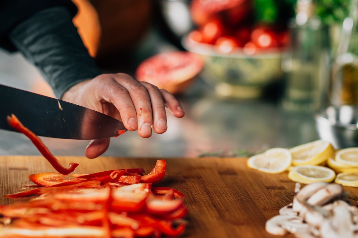 Cooking dinner - Chef Holding a Knife and Cutting Red Bell Pepper Cooking skills include how to prep produce.