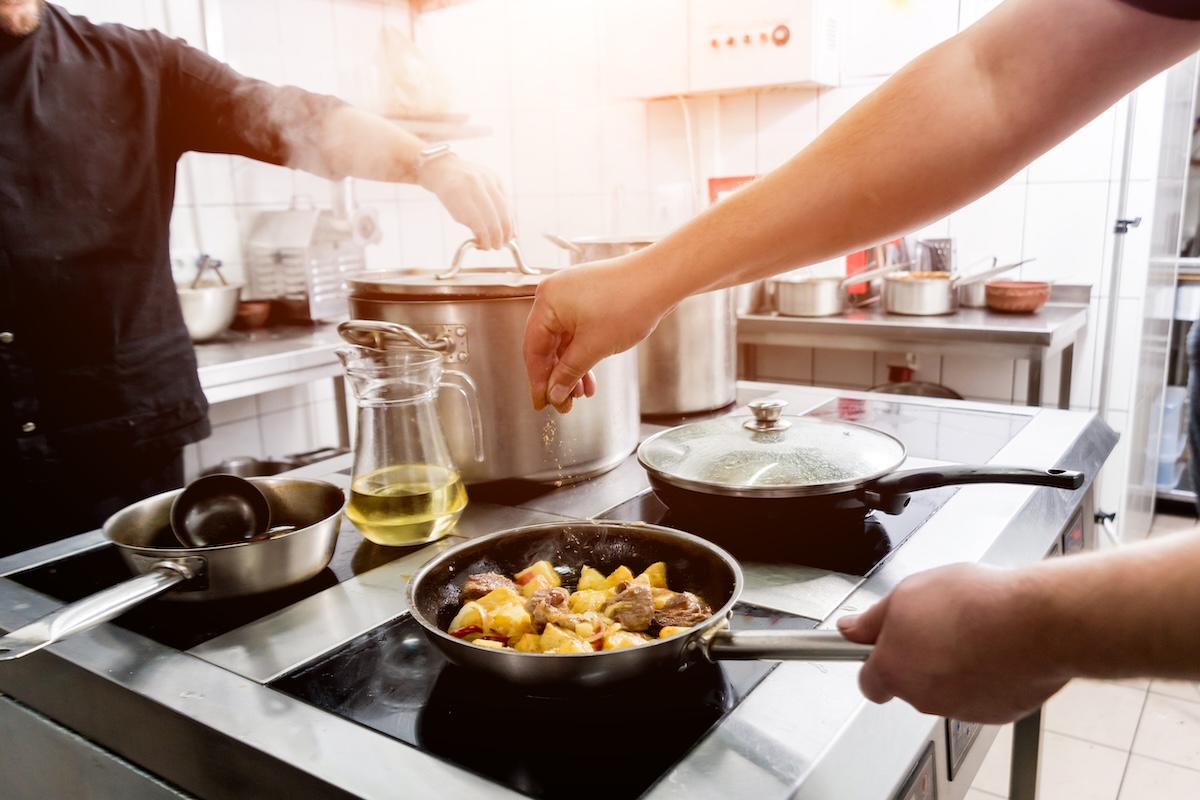Chef cooks fried potatoes with pieces of meat in a restaurant kitchen Cooking stills can help change lives.