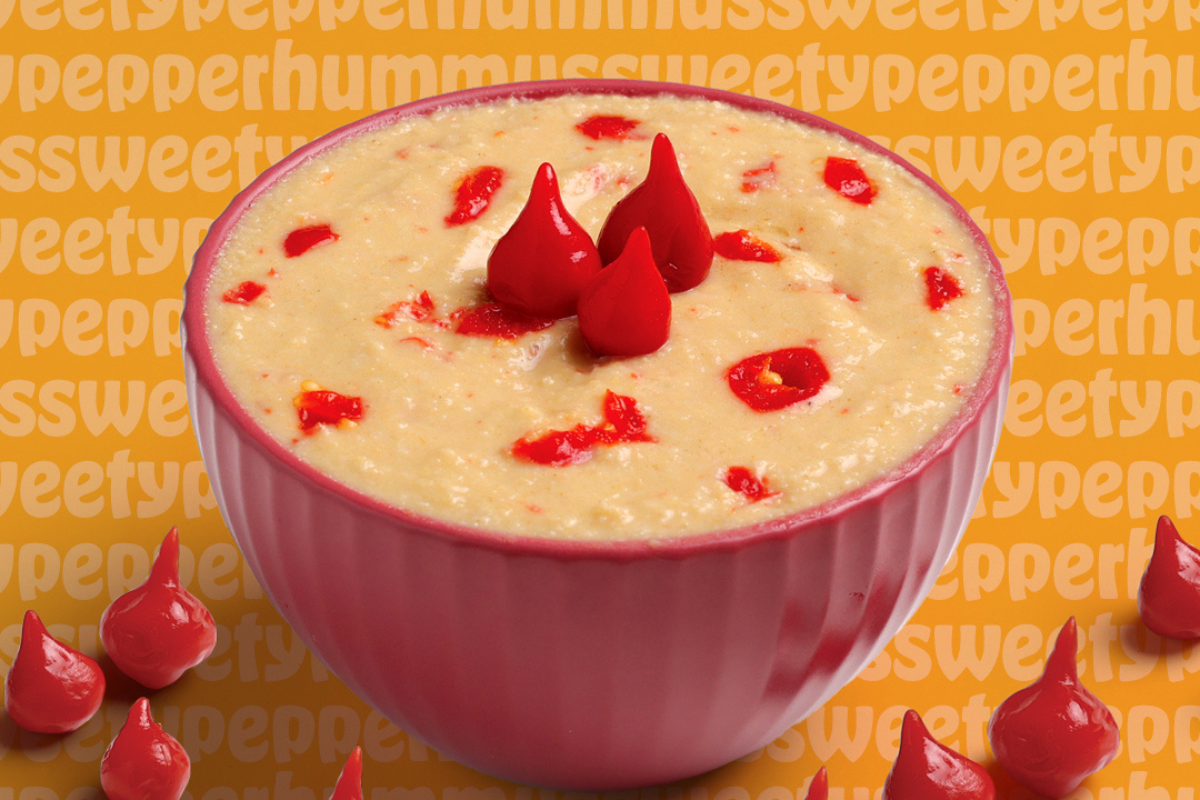 garbanzo fresh mediterranean A pink bowl of sweet pepper hummus topped with red pepper drops, set against a bold orange background with playful repeating text.