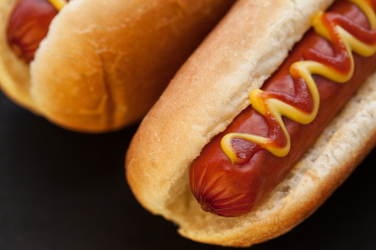 Barbecue Grilled Hot Dog with Yellow Mustard and ketchup on wooden table