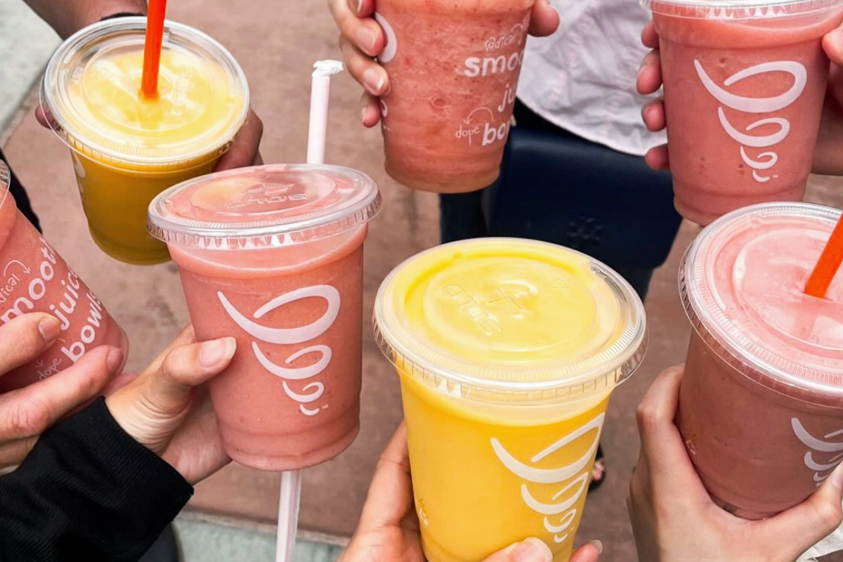 jamba juice A group of people holding colorful smoothies and juices from Jamba Juice, with a mix of yellow and pink drinks in clear plastic cups with lids and straws.