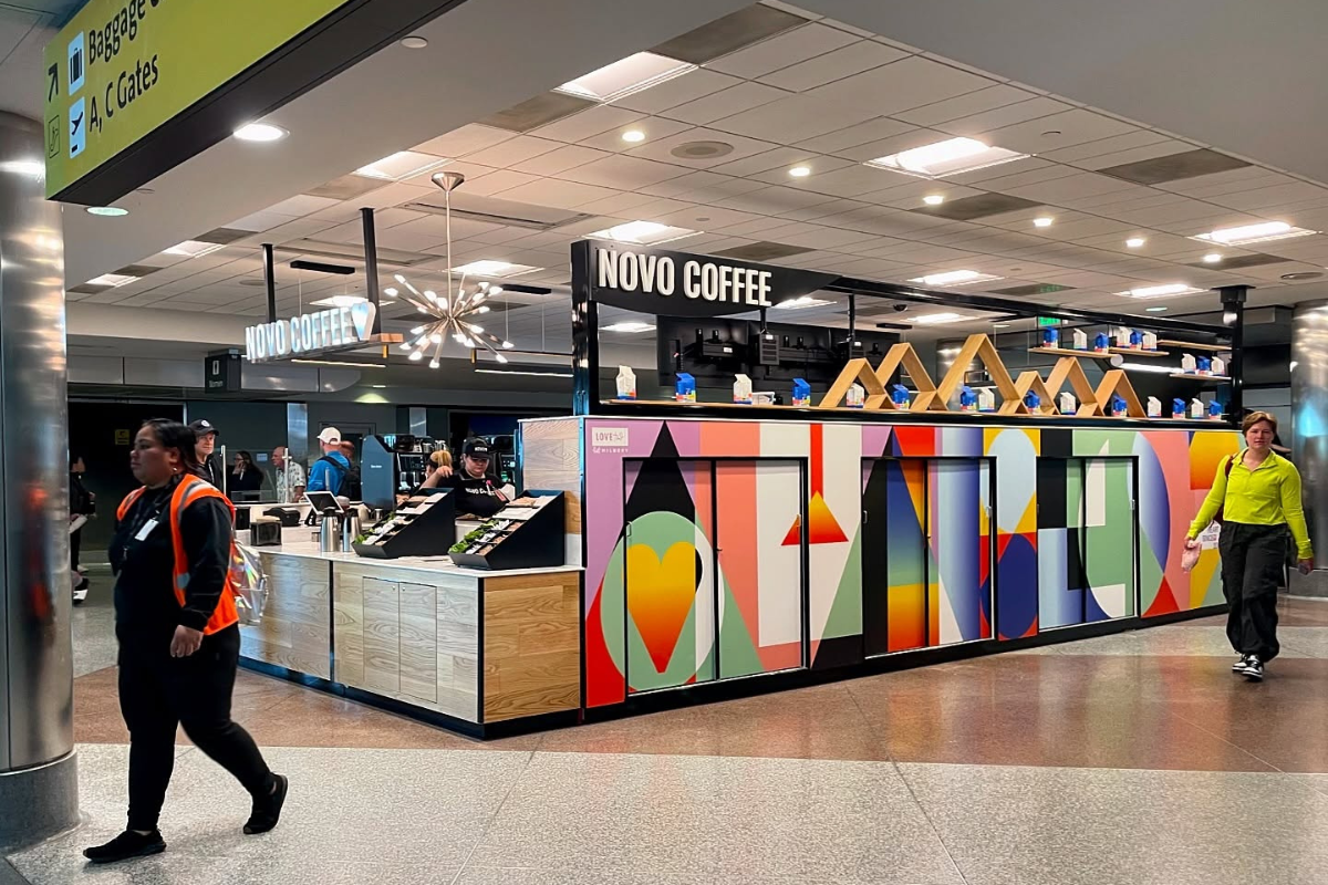 novo coffee Novo Coffee kiosk at the airport, featuring colorful wall art, modern lighting, and staff serving drinks to travelers walking by.
