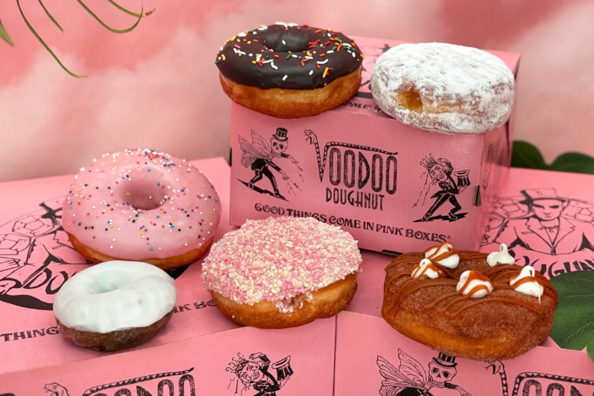 voodoo doughnut Voodoo Doughnut’s colorful variety of donuts displayed on signature pink boxes, including chocolate glazed, powdered, and sprinkle-covered options.