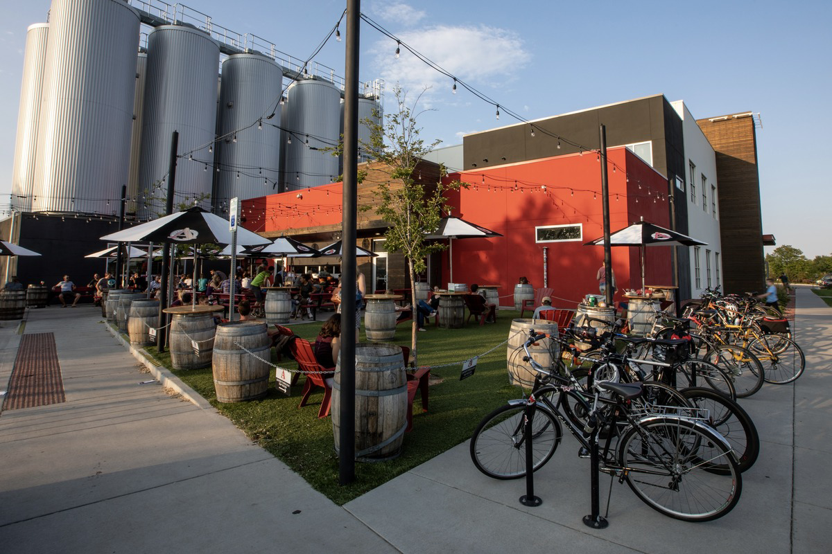 Avery_Brewing_Company Outdoor beer garden at Avery Brewing Company in Boulder, Colorado, featuring picnic tables, bike racks, string lights, and large brewing tanks.