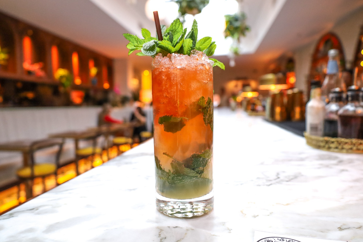 Ay Papi Mojito-style cocktail with mint, crushed ice, and a straw served on the marble bar at Ay Papi in Denver, a Puerto Rican-inspired cocktail bar.