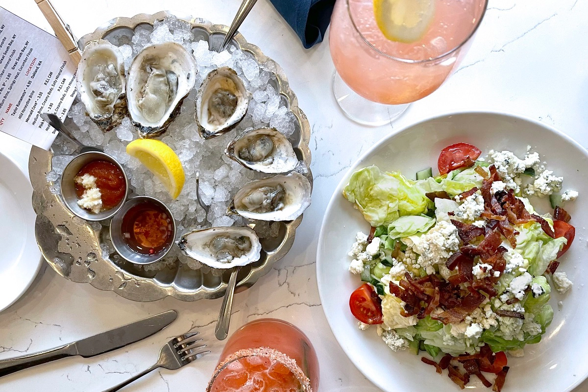Blue Island Oyster Bar Oysters on ice with sauces and lemon, served with a wedge salad topped with bacon and blue cheese at Blue Island Oyster Bar in Denver.