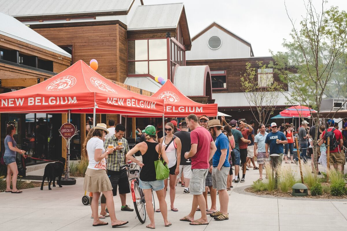 New_Belgium_Brewing_Company Crowd gathered at New Belgium Brewing Company in Fort Collins, Colorado, enjoying beer and tours under red tents at a lively outdoor brewery event.