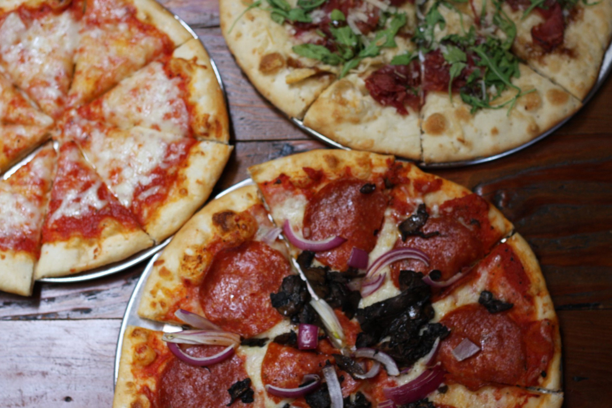 blackbird public house Three pizzas topped with cheese, pepperoni, mushrooms, red onion, arugula, and cured meats at Blackbird Public House in Denver.