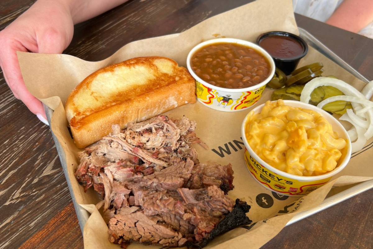 dickeys barbecue pit BBQ plate with sliced brisket, pulled pork, mac and cheese, baked beans, toast, pickles, and onions at Dickey’s Barbecue Pit in Denver.