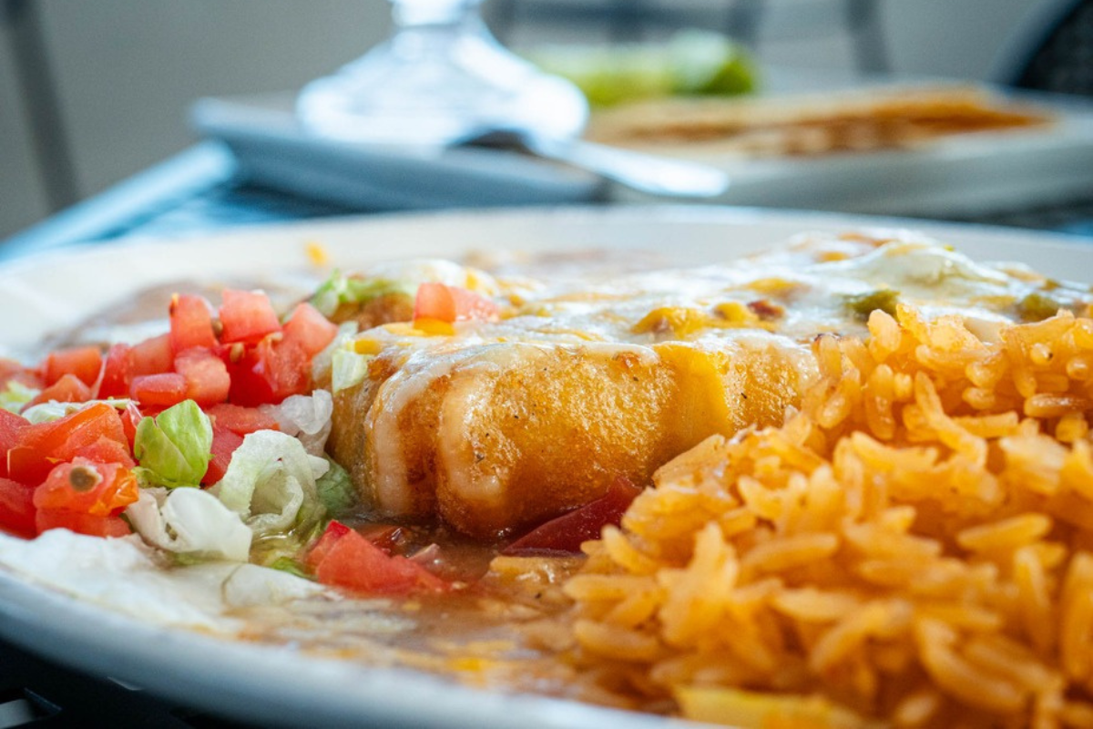 real de minas mexican restaurant Smothered burrito topped with melted cheese and served with rice, lettuce, and tomatoes at Real de Minas Mexican Restaurant in Denver.