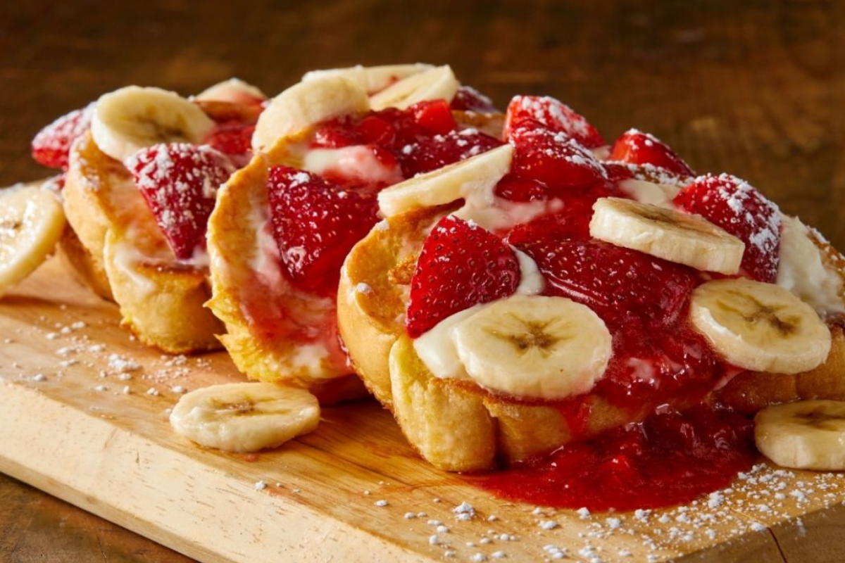 village inn Thick-cut French toast topped with strawberries, bananas, cream, and powdered sugar at Village Inn in Denver.